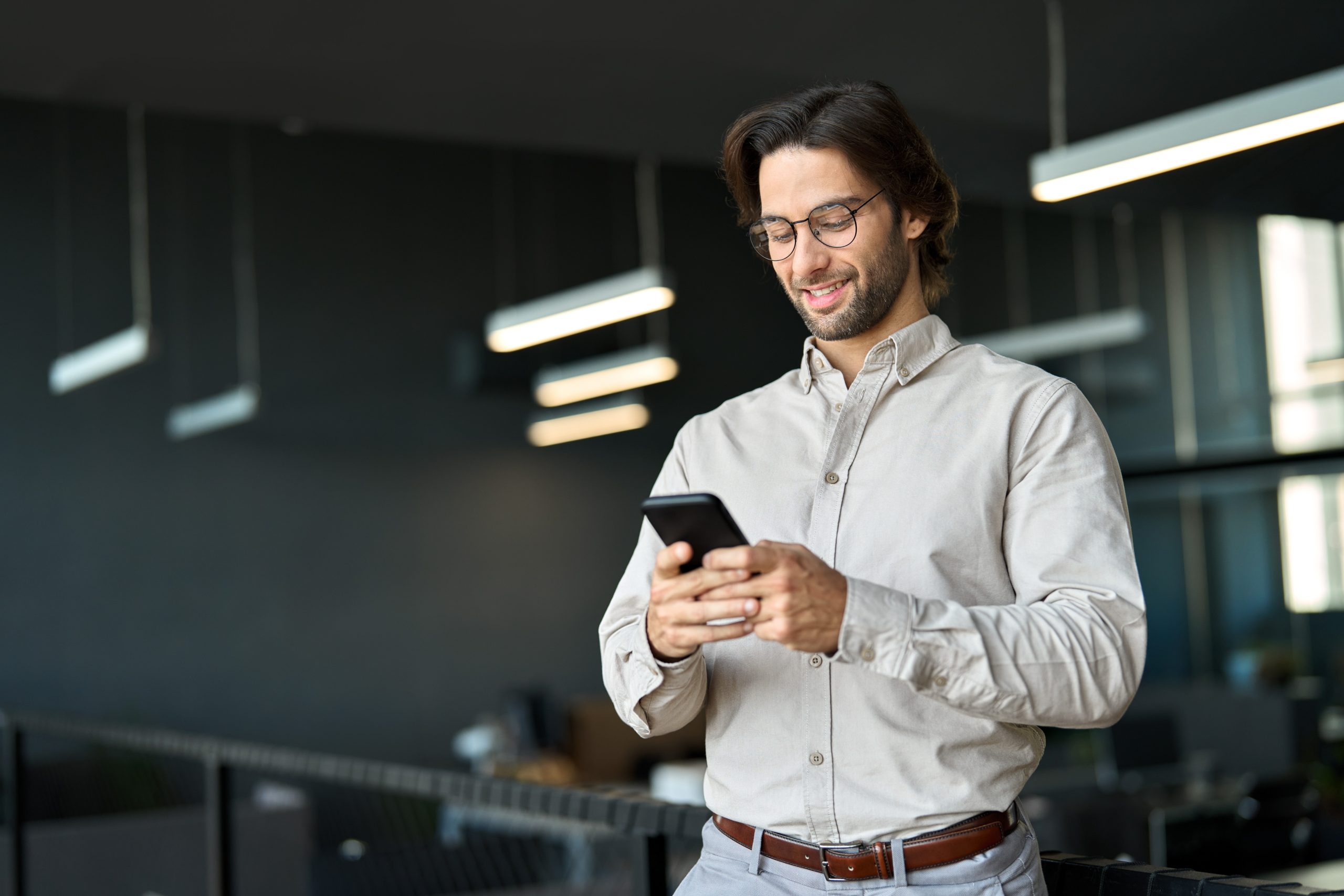 Busy,Young,European,Business,Man,Using,Cellphone,At,Work,Standing